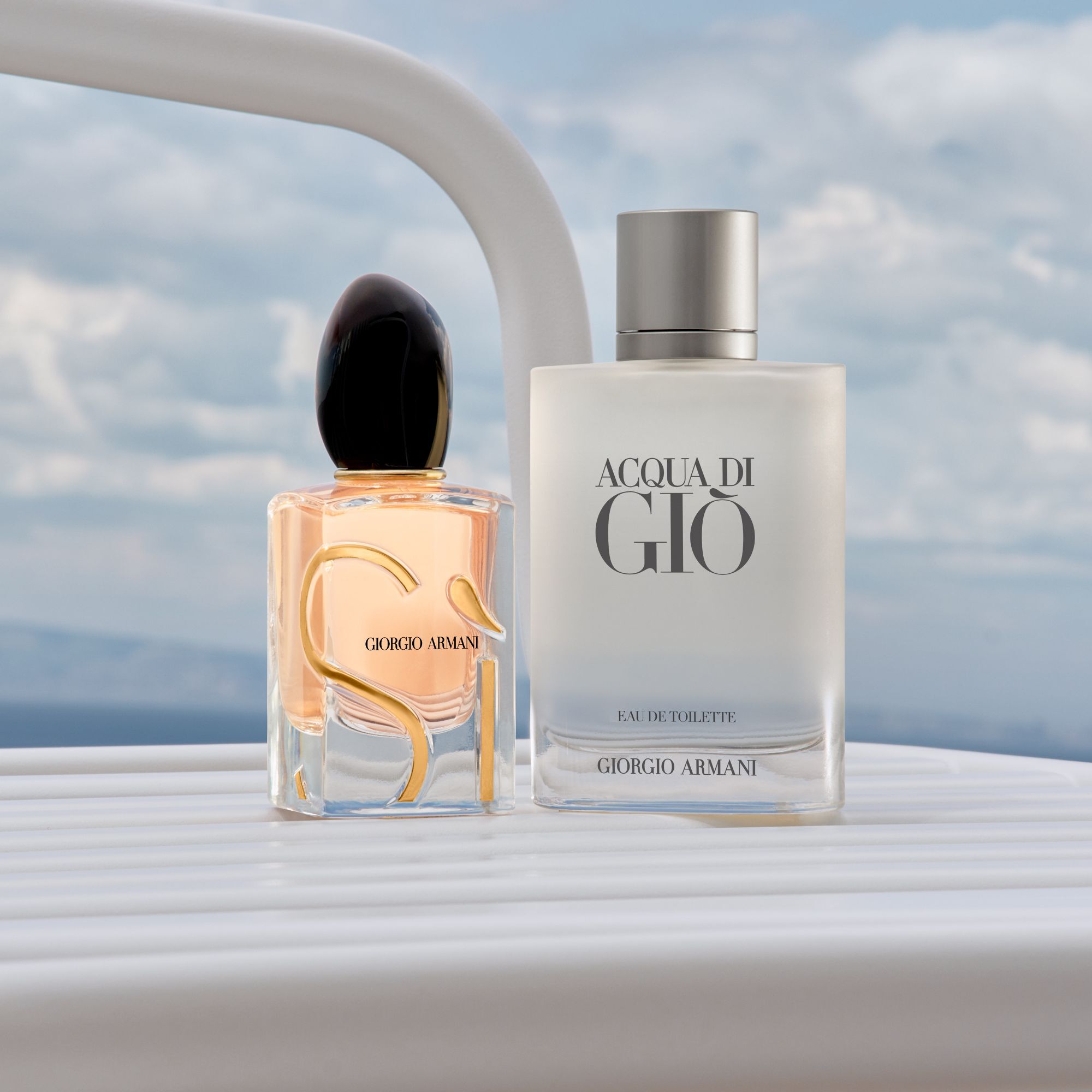 A sophisticated duo of Armani icons: the radiant Si and fresh Acqua di Gio. Standing on a sleek white yacht railing against a serene sea and sky, they embody a world of timeless elegance and the spirit of a luxurious coastal escape.