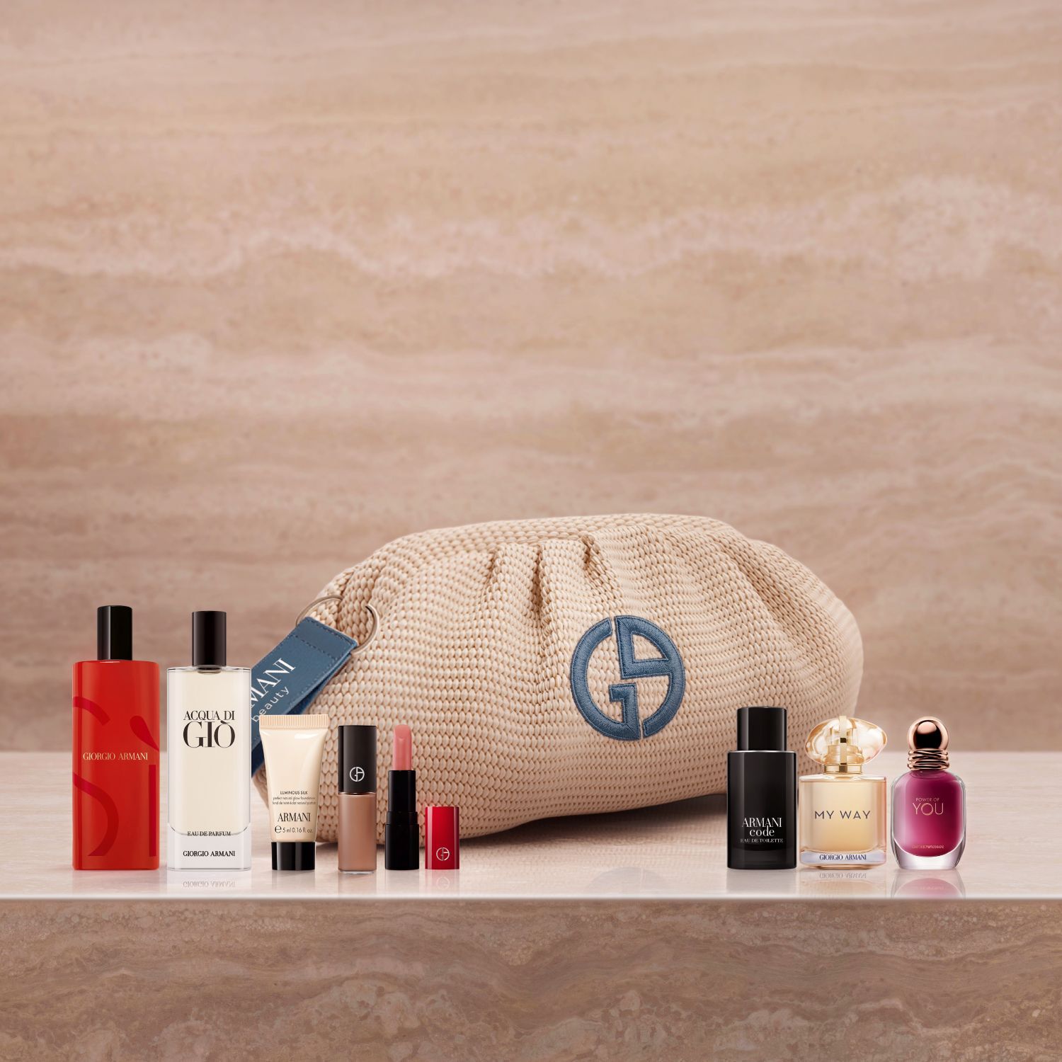 A luxurious lineup of Armani icons featuring Si, Acqua di Gio, and My Way fragrances, alongside Luminous Silk and an elegant lipstick. Set on marble with a woven beige pouch, this curated collection celebrates high-performance beauty.