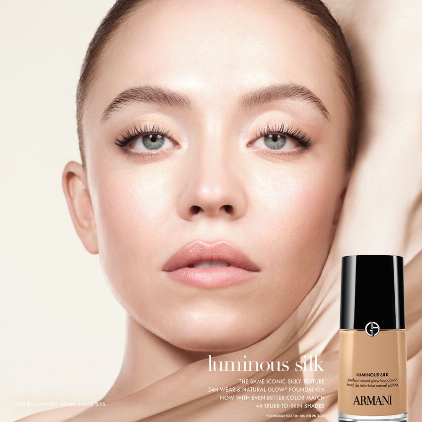 A close-up of Sydney Sweeney wearing Armani Luminous Silk foundation, with the product bottle shown in the bottom right corner.