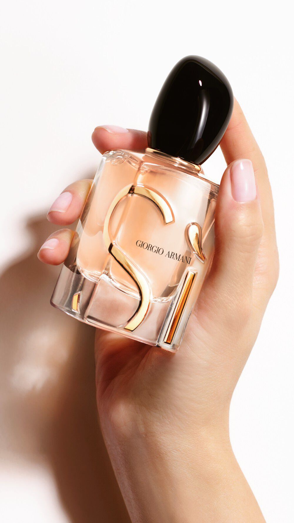 One hand holding a bottle of SI EAU DE PARFUM