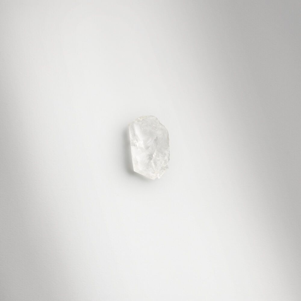 A single crystalline piece of musk, highlighting an essential note in Emporio Armani fragrance, rests on a minimalist white surface.