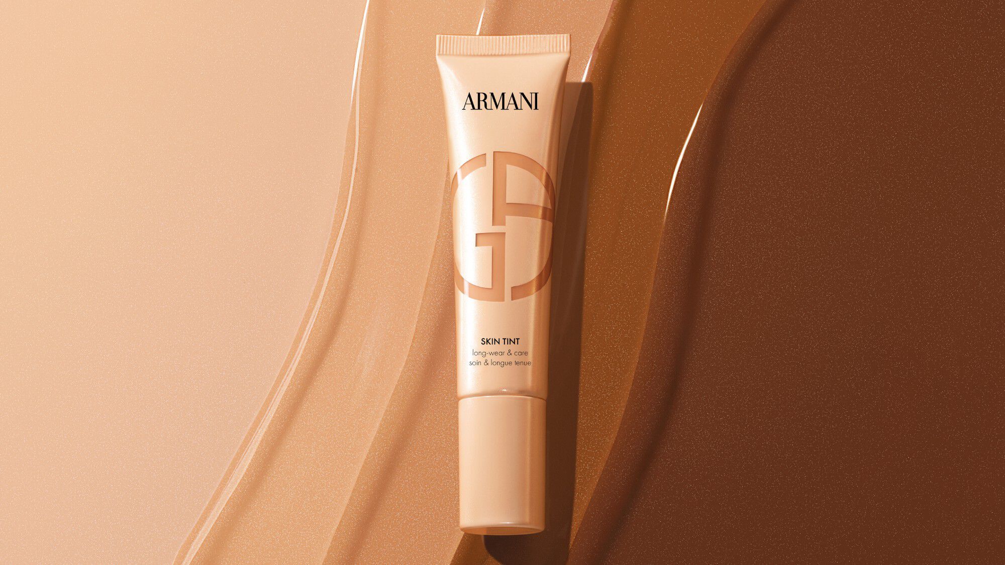 Armani Skin Tint tube on liquid foundation swatches of various shades.