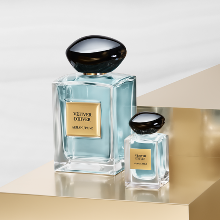The Armani/Prive: an iconic full-size bottle and its elegant miniature, revealing a pale green essence. Set on a radiant gold pedestal, they celebrate the serene balance of tea and the House's artisanal couture luxury.
