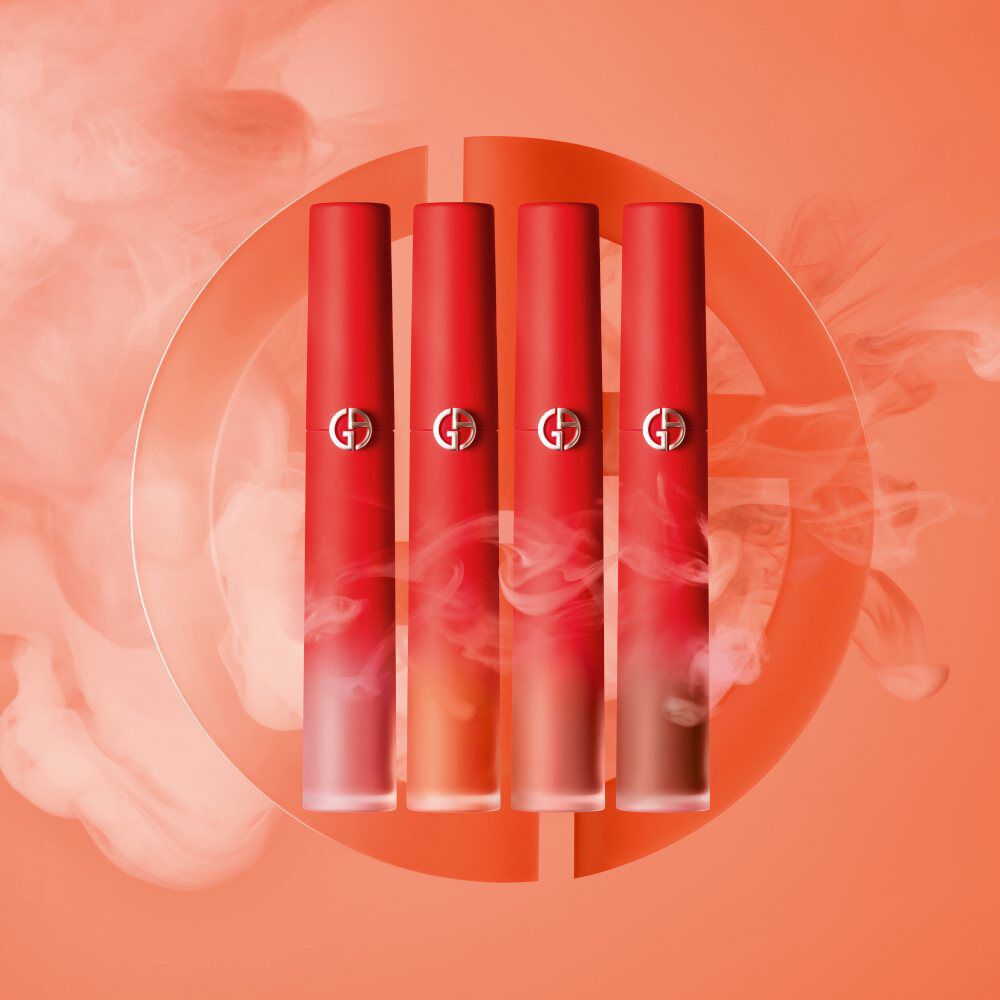 Four gradient red lip product tubes arranged in a row against an orange background with subtle smoke effects.