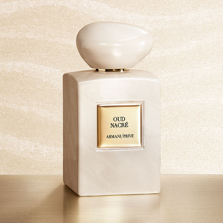  Armani/Prive Oud Nacre: an iridescent pearlescent bottle with a soft-sculpted cap, standing on a gold pedestal against a shimmering backdrop. A luminous tribute to the precious nobility of Oud and the art of haute couture perfumery at its finest.