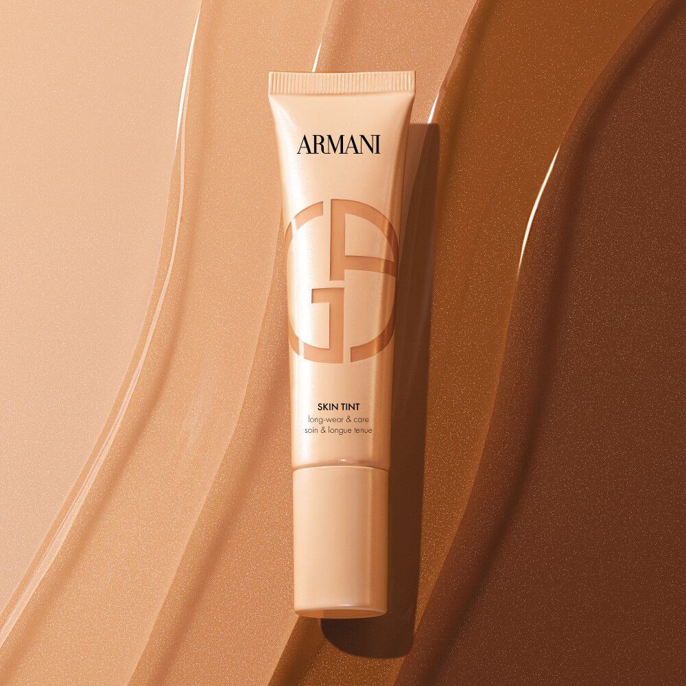 Armani Skin Tint tube on liquid foundation swatches of various shades.