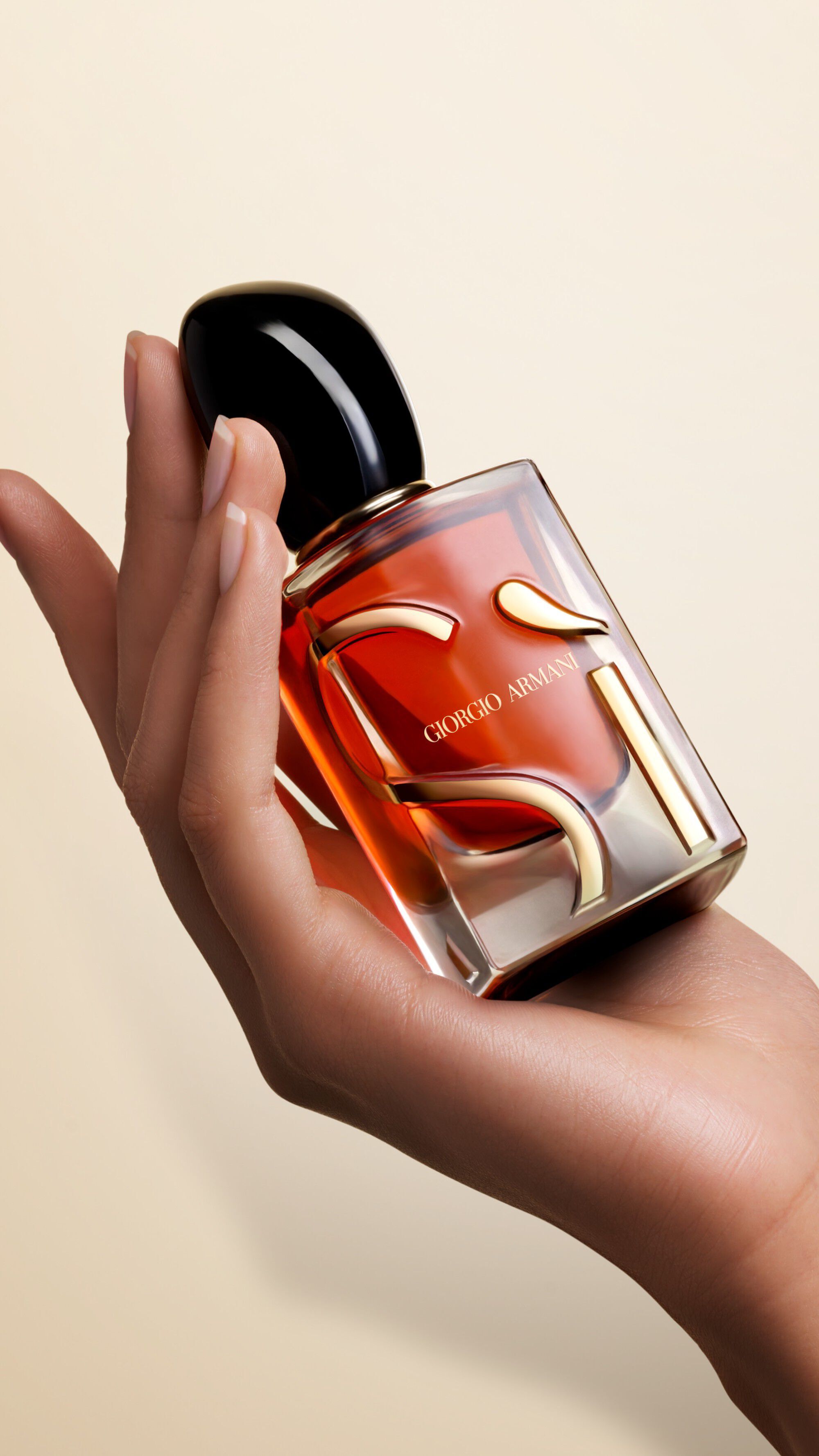 One hand holding a bottle of SI PARFUM