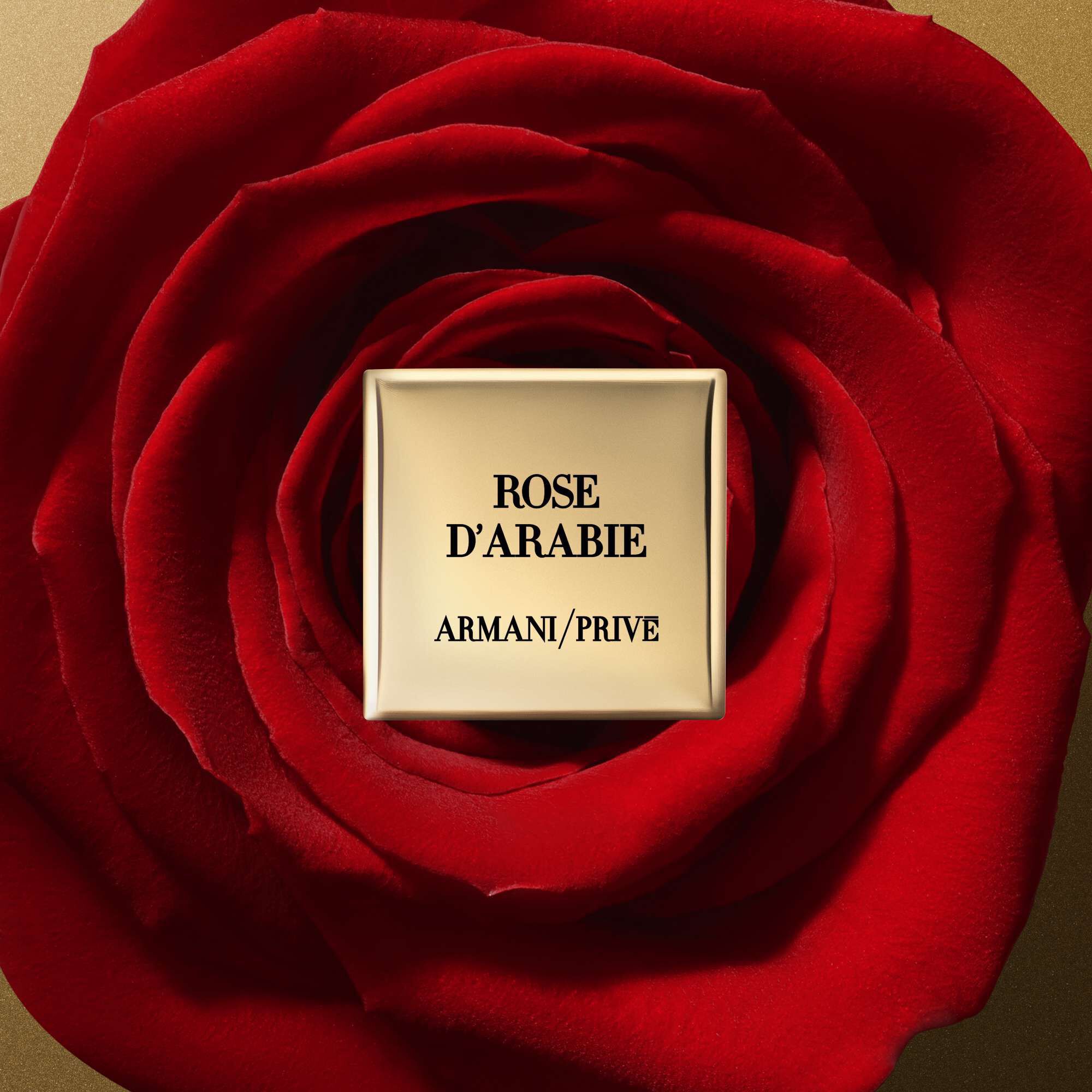 A close-up of a red rose with a gold square label in the center that reads "ROSE D'ARABIE" and "ARMANI/PRIVE."