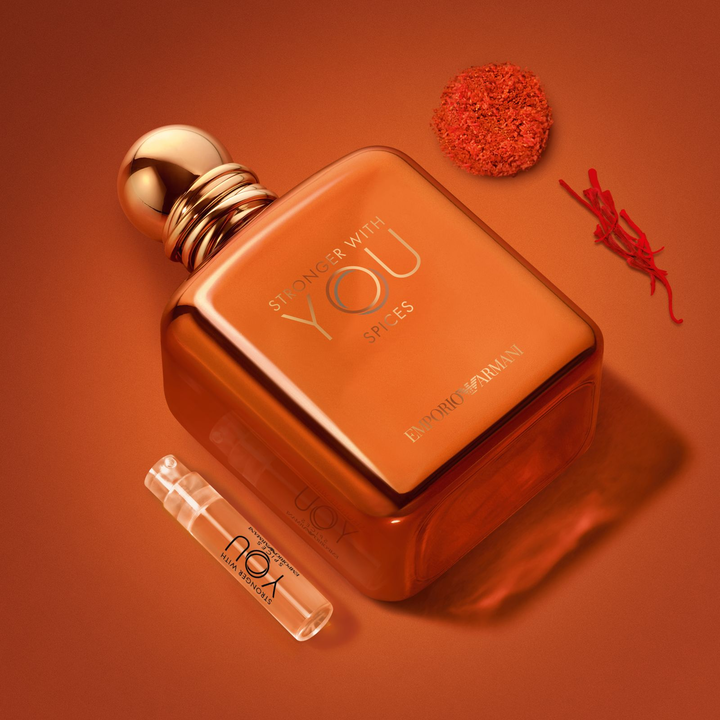 A radiant Stronger With You Spices bottle and its discovery vial, nestled among saffron strands and spice accords. A magnetic visual capturing the vibrant, warm, and spicy essence of this solar masculine fragrance of absolute luxury.