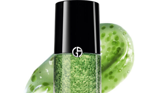 A bottle of green gel with a black cap, surrounded by a green, gel-like swirl. The packaging features a logo with the letters "GA."
