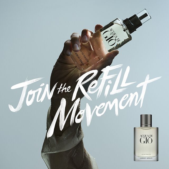 Hand holding Acqua di Gio Eau de Toilette bottle against a pale blue background. Text reads: "Join the Refill Movement. Discover our range of refillable fragrances." Giorgio Armani.