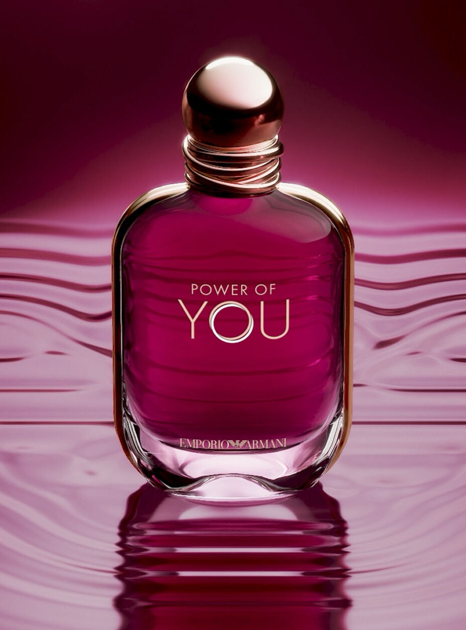 The Armani Power of You perfume bottle resting on its radiant ruby liquid, reflecting light and the fragrance’s luminous energy.
