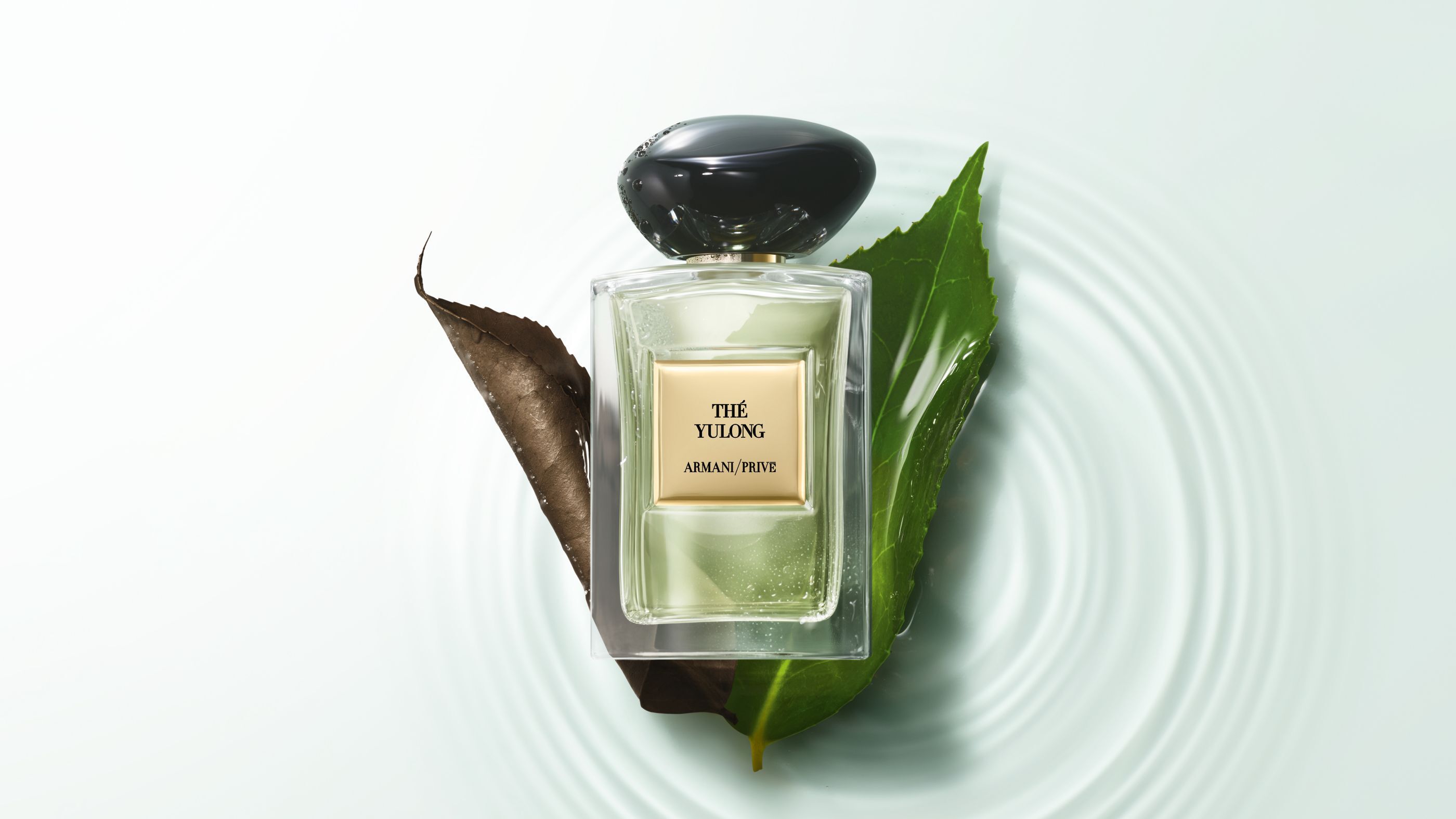 Armani/Prive "The Yulong" perfume bottle resting on leaves over rippling water.