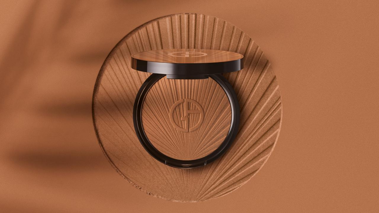 A sleek compact with a geometric design and logo, set against a warm, textured brown background.