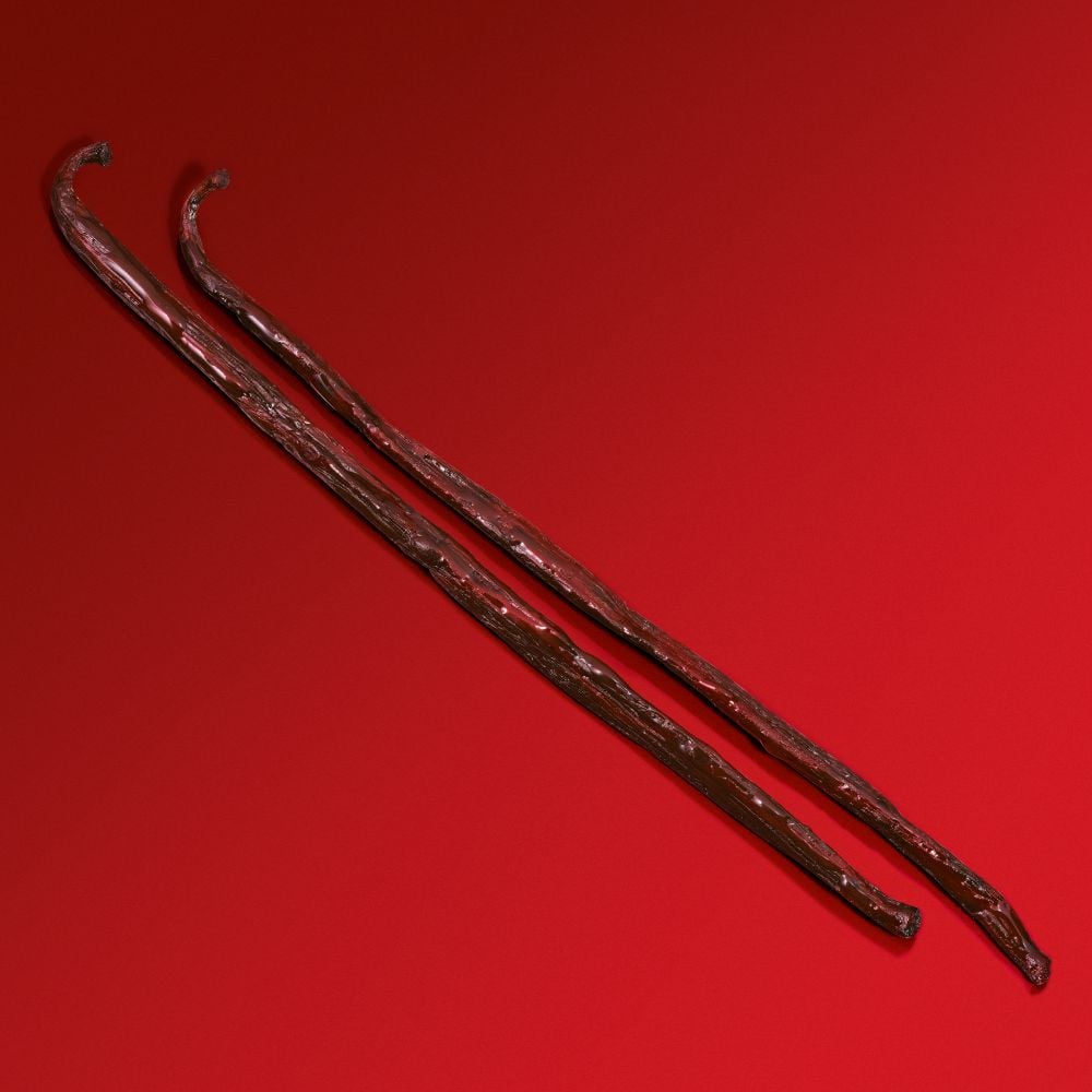 Two twisted, brownish red sticks resembling old wooden canes, displayed against a vibrant red background.